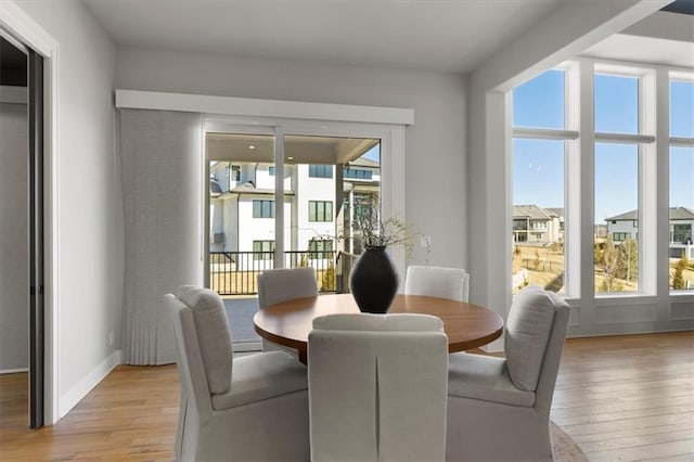 dining space featuring light wood-type flooring and baseboards