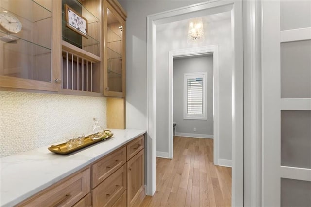 bar featuring tasteful backsplash, light wood finished floors, and baseboards