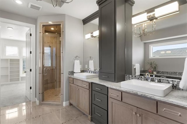 full bathroom featuring double vanity, a stall shower, visible vents, and a sink