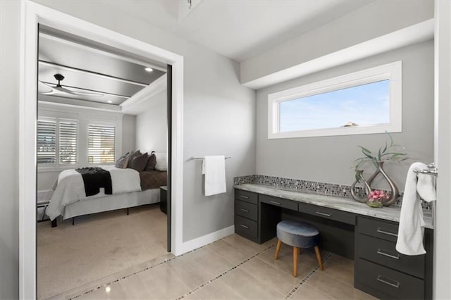 interior space featuring light colored carpet, built in desk, baseboards, and light tile patterned floors