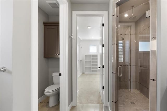 bathroom featuring toilet, a shower stall, visible vents, and baseboards