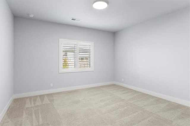 spare room with carpet floors, visible vents, and baseboards