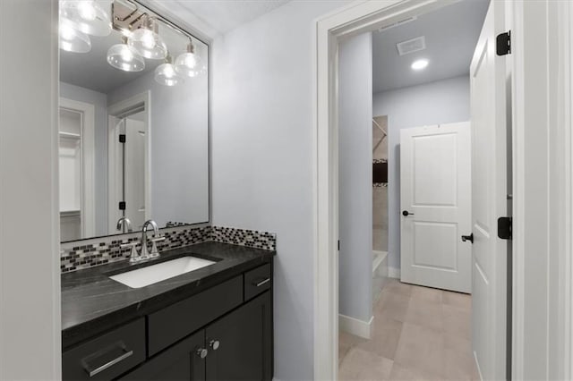 bathroom with a walk in closet, visible vents, decorative backsplash, and vanity