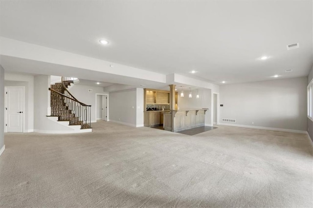 unfurnished living room featuring baseboards, stairway, visible vents, and recessed lighting