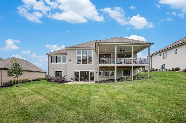 rear view of property featuring ceiling fan, a lawn, a patio area, and stucco siding