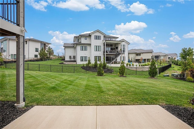 rear view of property featuring a yard, a balcony, a residential view, and fence