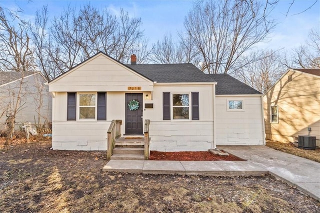 bungalow-style house featuring a shingled roof, a chimney, and central AC unit