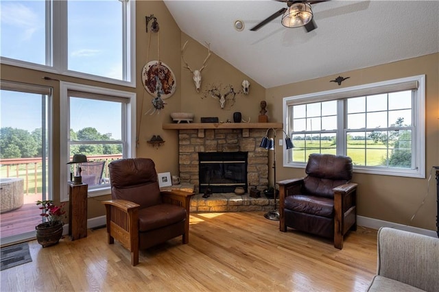 living room featuring a ceiling fan, light wood-type flooring, a healthy amount of sunlight, and a fireplace