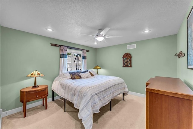 bedroom featuring baseboards, visible vents, a ceiling fan, light colored carpet, and a textured ceiling