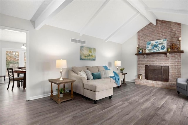 living area with visible vents, a fireplace, vaulted ceiling with beams, and wood finished floors