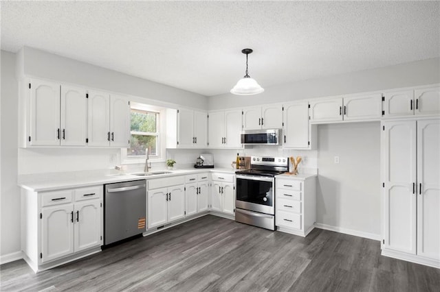 kitchen featuring appliances with stainless steel finishes, white cabinetry, dark wood-type flooring, and a sink