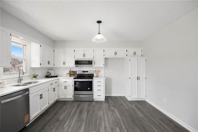 kitchen with a sink, white cabinets, dark wood-style floors, and stainless steel appliances