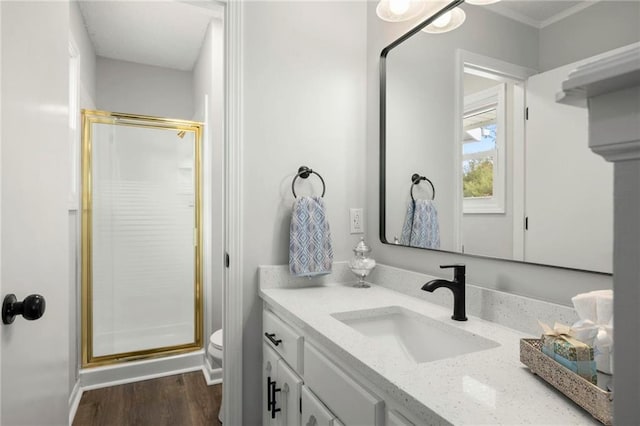 bathroom featuring wood finished floors, toilet, a stall shower, and vanity