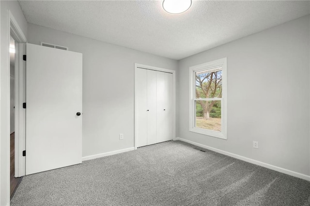 unfurnished bedroom with carpet, baseboards, visible vents, a closet, and a textured ceiling