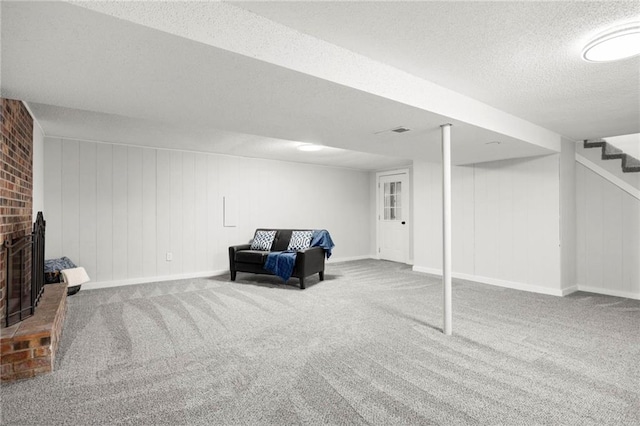 finished basement featuring stairway, a fireplace, carpet floors, and a textured ceiling