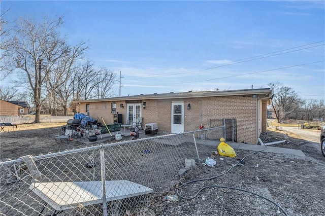 back of house featuring brick siding, a patio area, fence, and french doors