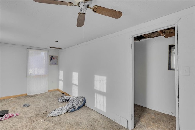 carpeted empty room featuring ceiling fan and baseboards