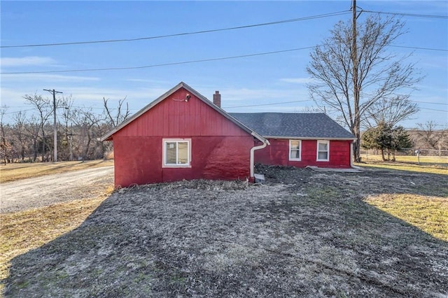 view of property exterior with roof with shingles and a chimney