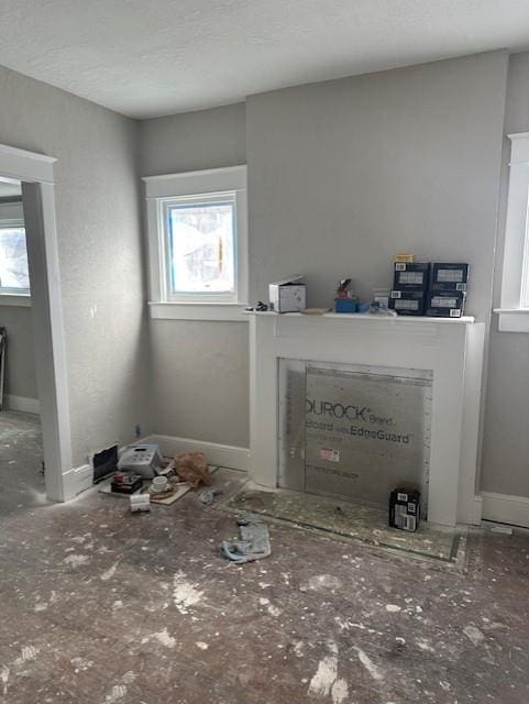 unfurnished living room featuring baseboards, a wealth of natural light, and a textured ceiling