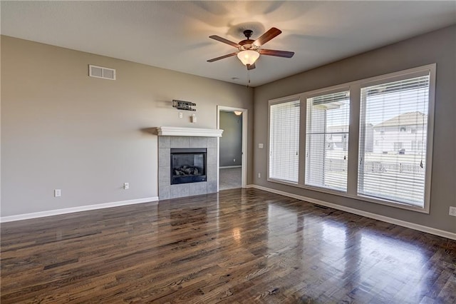 unfurnished living room with visible vents, a tile fireplace, baseboards, and dark wood-style flooring