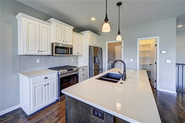 kitchen with a sink, dark wood-style floors, appliances with stainless steel finishes, white cabinets, and decorative backsplash