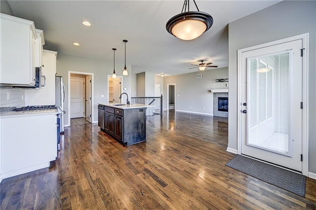 kitchen with a sink, backsplash, dark wood-style flooring, and light countertops