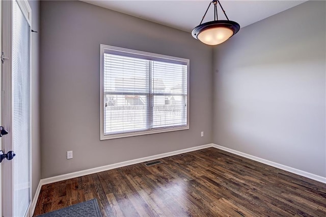 unfurnished room with visible vents, baseboards, and dark wood-type flooring