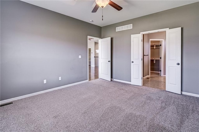 unfurnished bedroom featuring visible vents, carpet floors, baseboards, and a spacious closet