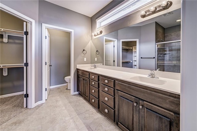 bathroom with a sink, toilet, double vanity, and a shower stall