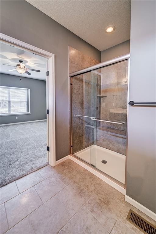 full bath featuring visible vents, baseboards, a stall shower, a textured ceiling, and a ceiling fan