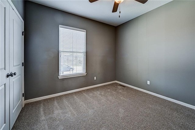 spare room with baseboards, carpet, and a ceiling fan