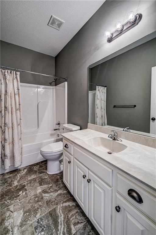 bathroom with visible vents, toilet, vanity, and a textured ceiling