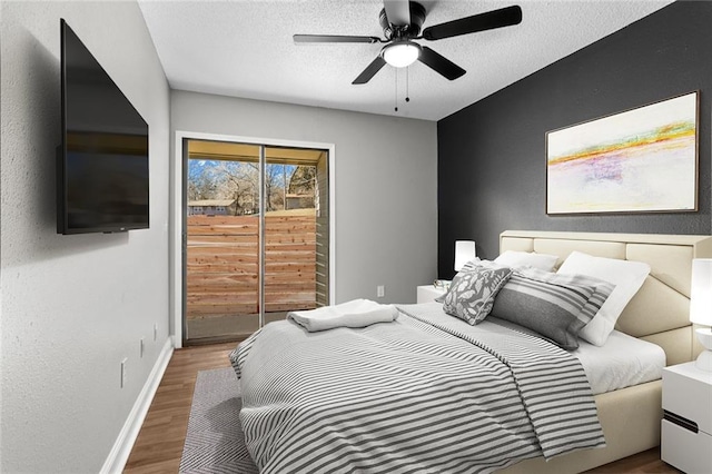 bedroom featuring ceiling fan, a textured ceiling, wood finished floors, access to outside, and baseboards