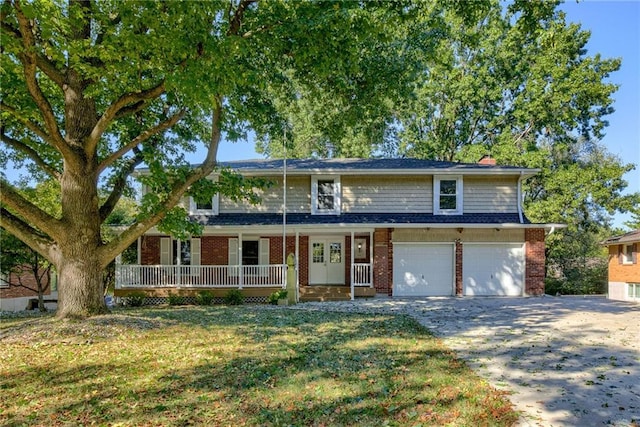 traditional home featuring brick siding, covered porch, a garage, driveway, and a front lawn