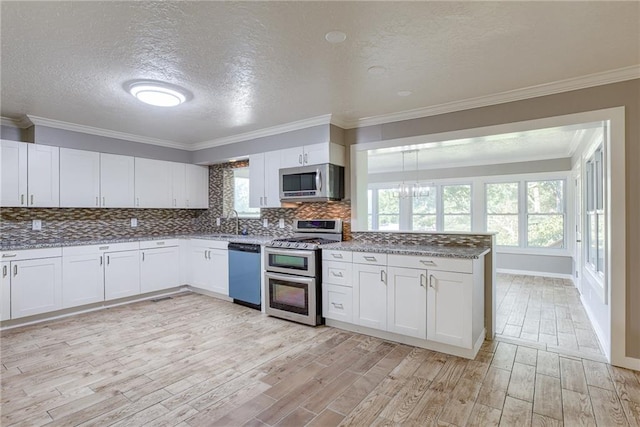 kitchen with light wood finished floors, stainless steel appliances, decorative backsplash, white cabinets, and a sink