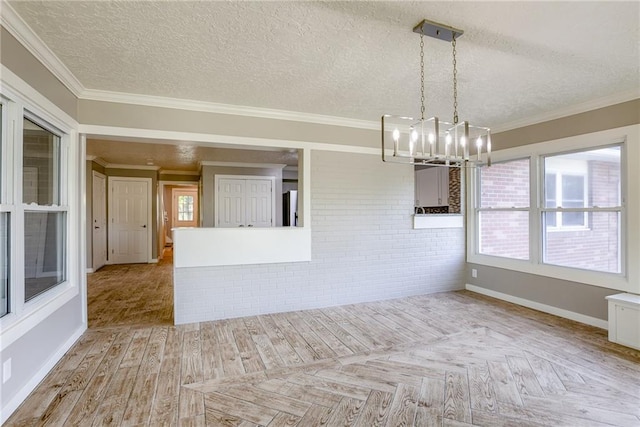 spare room with parquet floors, a textured ceiling, ornamental molding, and a notable chandelier