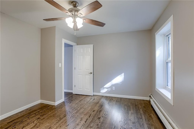 unfurnished room featuring baseboard heating, plenty of natural light, wood finished floors, and baseboards