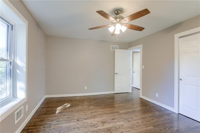 unfurnished room featuring wood finished floors, visible vents, and baseboards