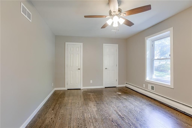 unfurnished bedroom with a baseboard heating unit, wood finished floors, a ceiling fan, visible vents, and baseboards