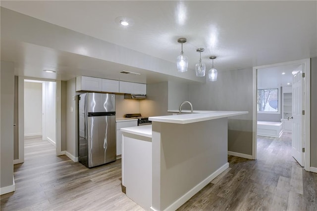 kitchen featuring stainless steel appliances, light wood finished floors, light countertops, and white cabinets