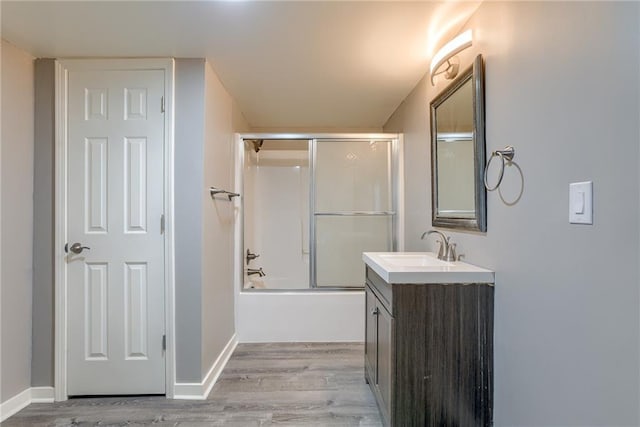 full bath with bath / shower combo with glass door, vanity, baseboards, and wood finished floors