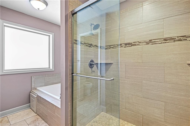 full bathroom with a garden tub, a shower stall, baseboards, and tile patterned floors