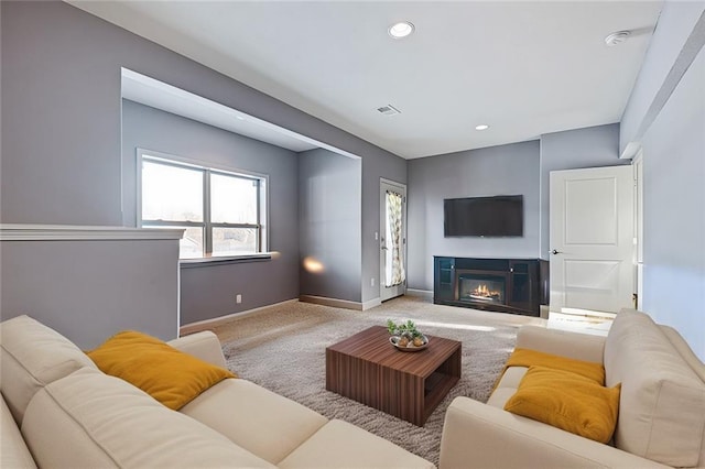 carpeted living room with recessed lighting, visible vents, baseboards, and a glass covered fireplace