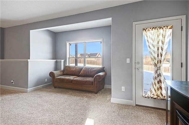 carpeted living area featuring baseboards