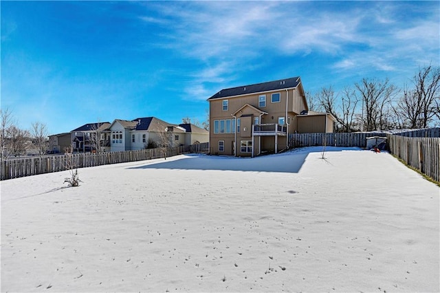 snow covered house with a residential view and a fenced backyard