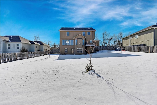 snow covered rear of property featuring a fenced backyard