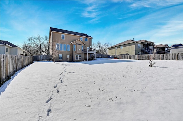 snow covered property featuring a fenced backyard and a residential view