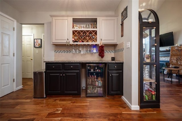 bar with a dry bar, beverage cooler, tasteful backsplash, and dark wood finished floors