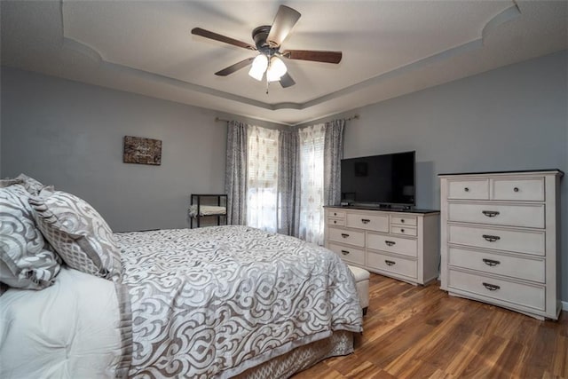 bedroom featuring a ceiling fan, a tray ceiling, and wood finished floors