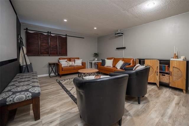 living area featuring a textured ceiling, light wood finished floors, baseboards, and recessed lighting